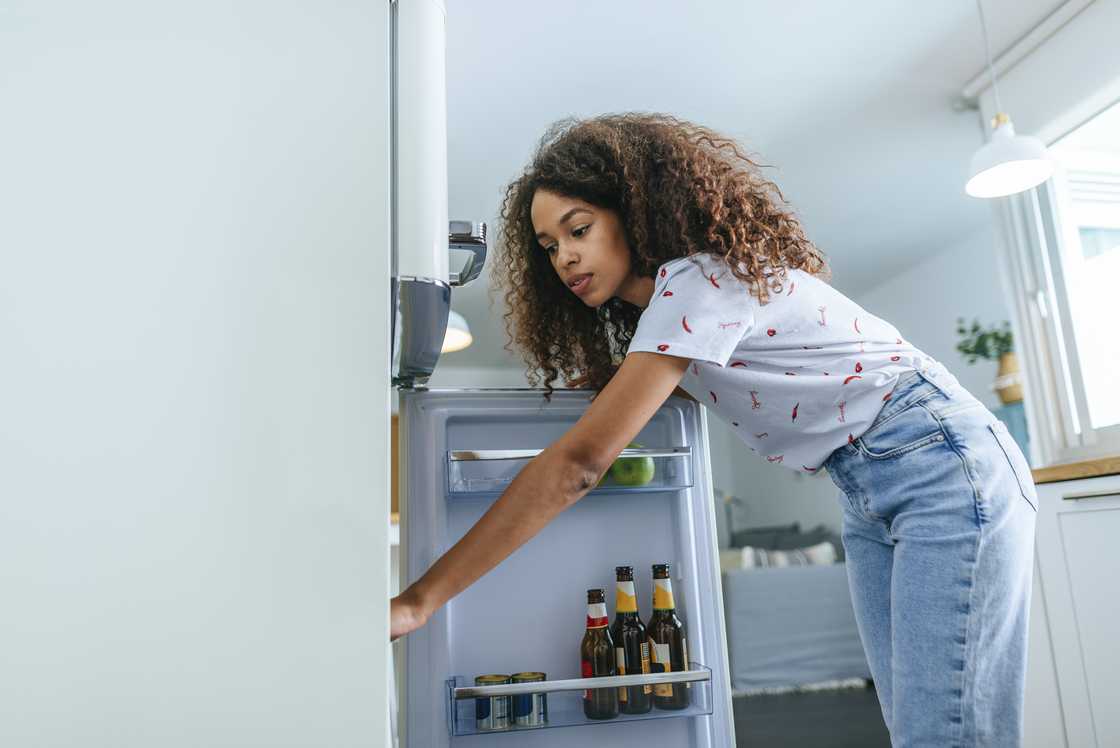 A woman is opening the fridge