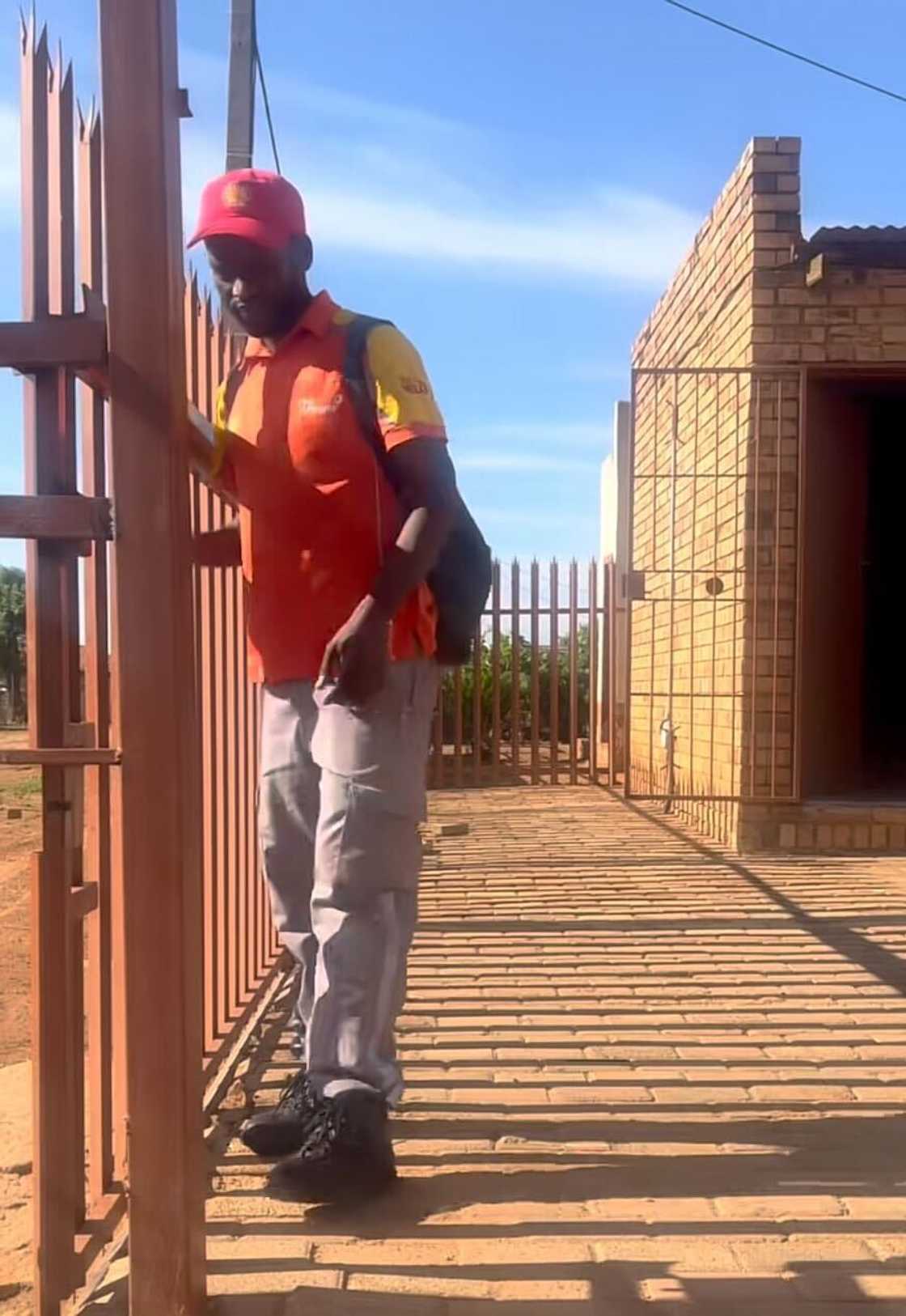 A petrol attendant in South Africa opening the gate to his house after returning from work. A petrol attendant in South Africa opening the gate to his house after returning from work.