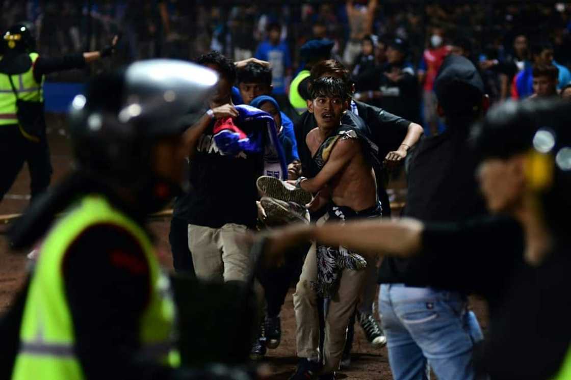 A group of people carry a man off the field at Kanjuruhan stadium on the night of the disaster A group of people carry a man off the field at Kanjuruhan stadium on the night of the disaster