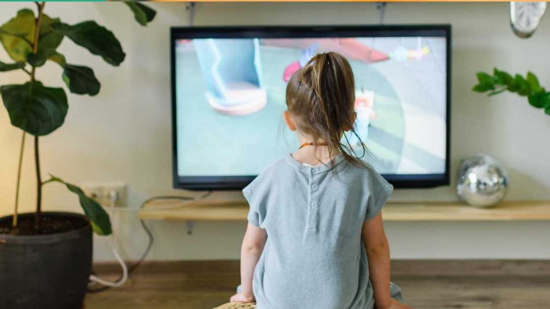 A young girl watching the TV