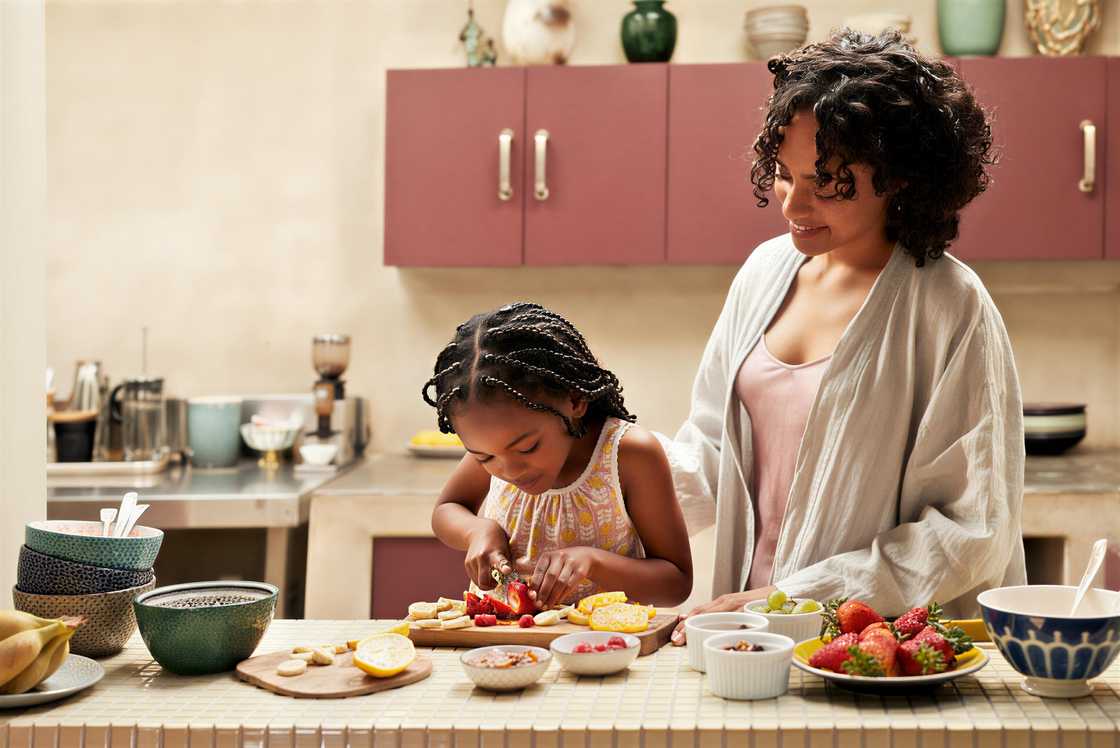 A smiling woman standing by her daughter
