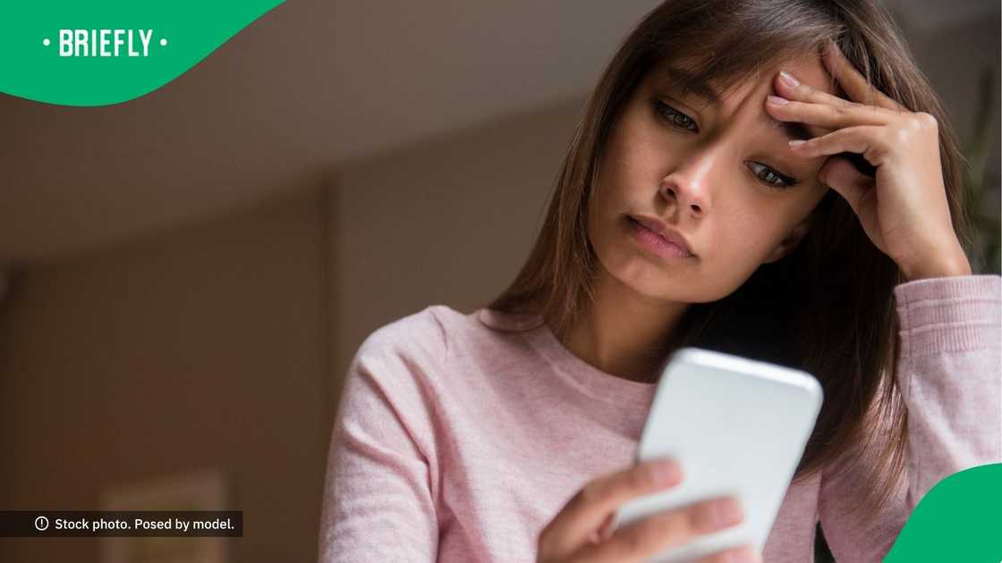A concerned woman looking at her phone.