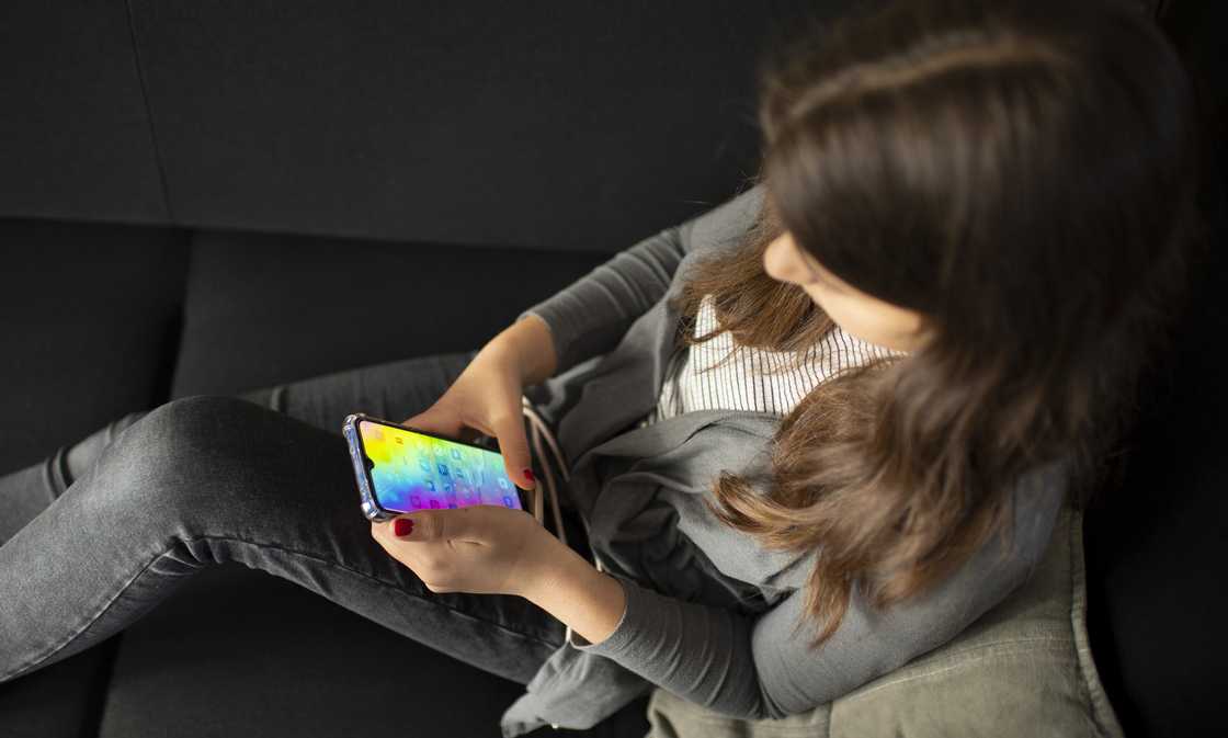 In this photo illustration a girl sits on a sofa using her smartphone on April 14, 2021 in Bonn, Germany