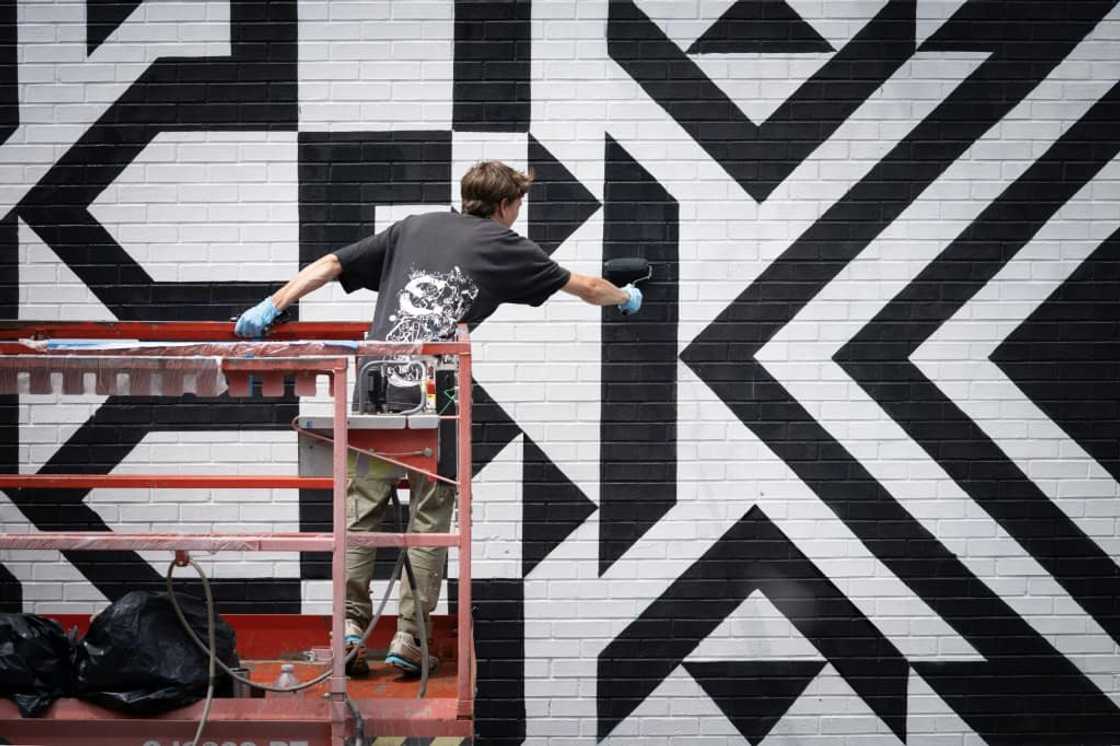 An assistant of mural artist Caroline Monnet paints during the Mural festival in Montreal, Quebec on June 16, 2022 An assistant of mural artist Caroline Monnet paints during the Mural festival in Montreal, Quebec on June 16, 2022
