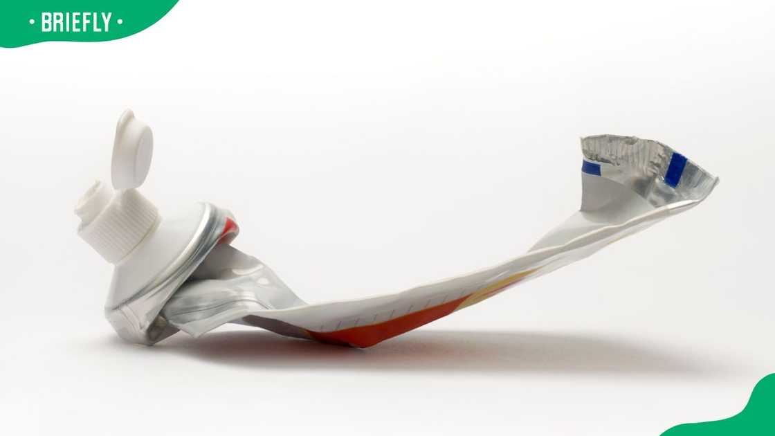 A toothpaste container squeezed empty on a white background A toothpaste container squeezed empty on a white background