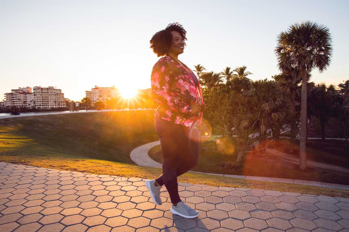 Woman walking alone through a quiet city park at dusk.