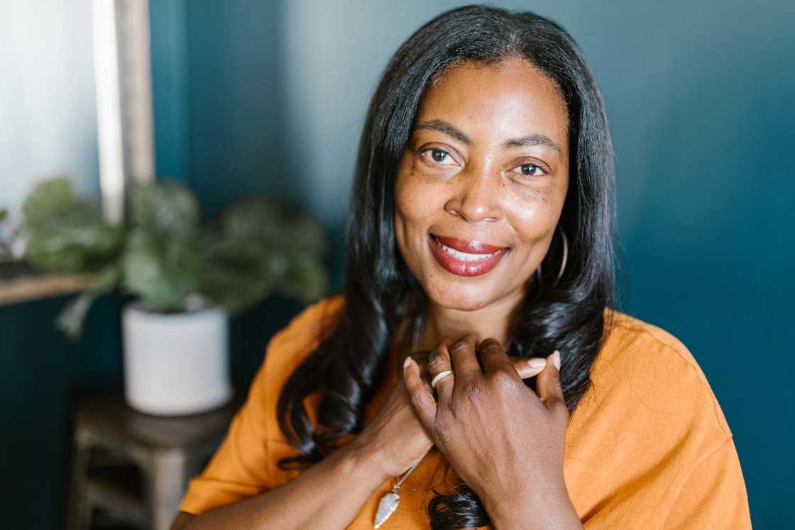 A woman smiles gently while holding her hands to her chest.