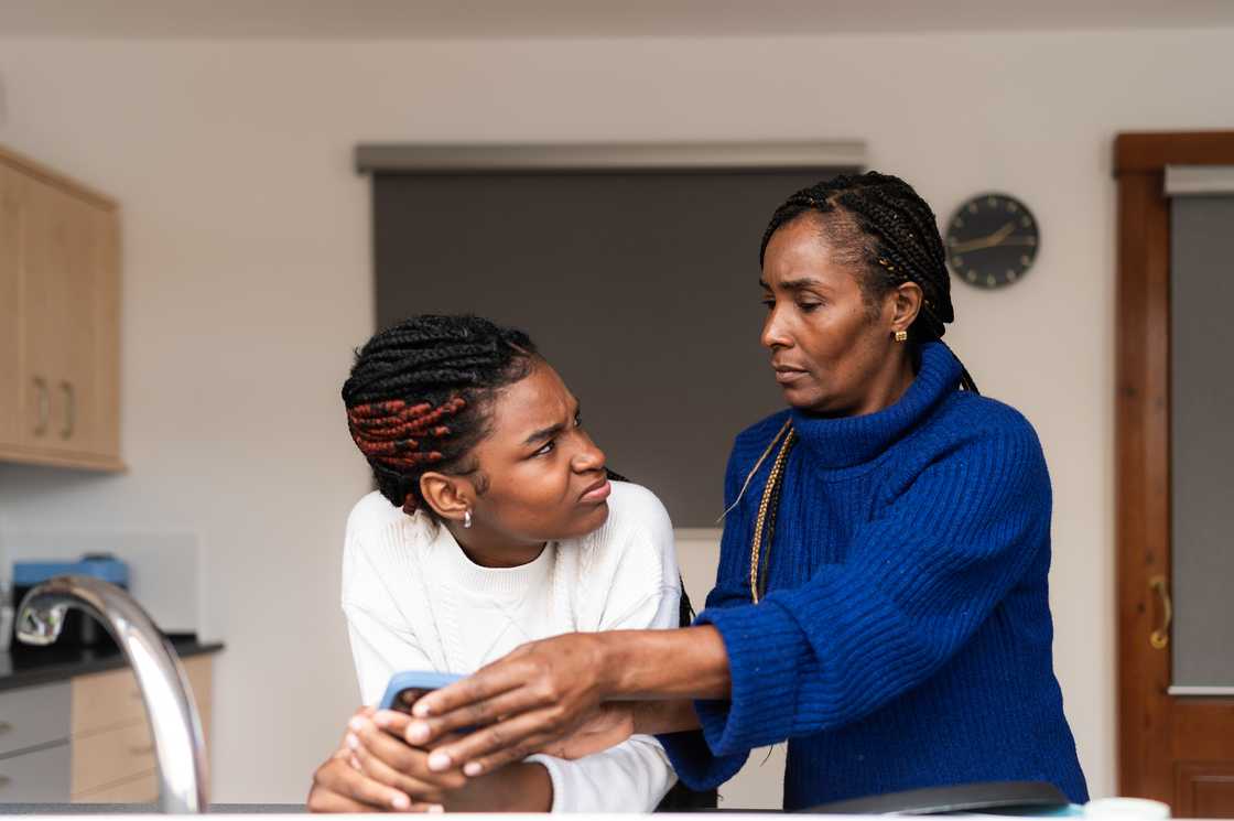 A mother confiscating daughter’s phone. A mother confiscating daughter’s phone.