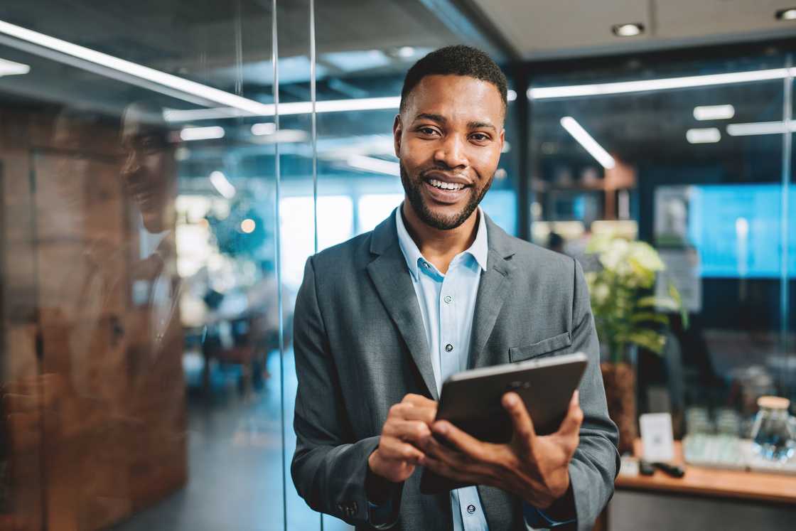 Businessman looking at camera holding digital tablet