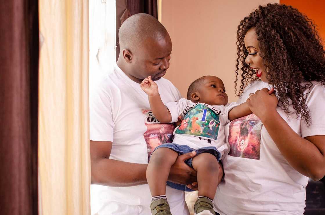 Smiling parents hold their baby indoors. Smiling parents hold their baby indoors.