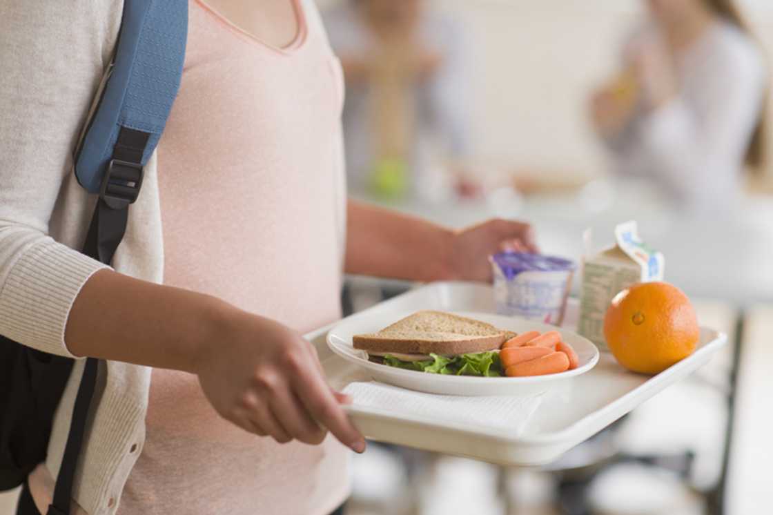 A young pupil carrying her food during lunchtime at school. A young pupil carrying her food during lunchtime at school.
