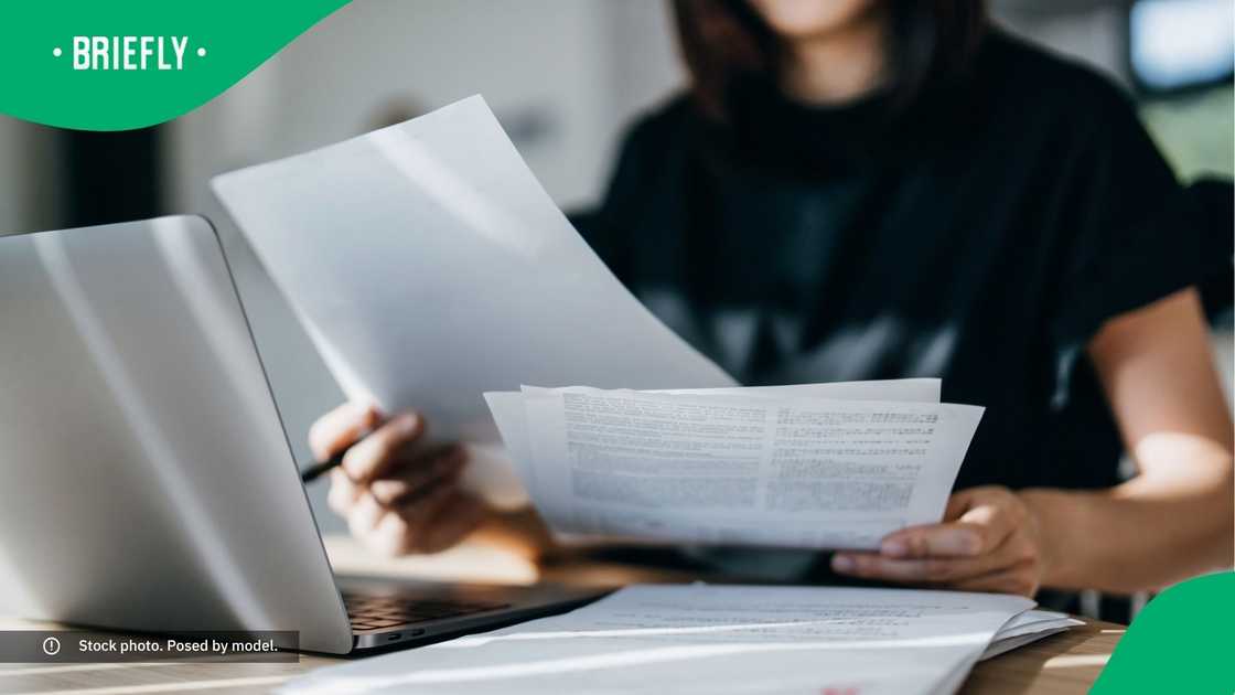 A woman sitting at her desk filled with documents and her laptop.