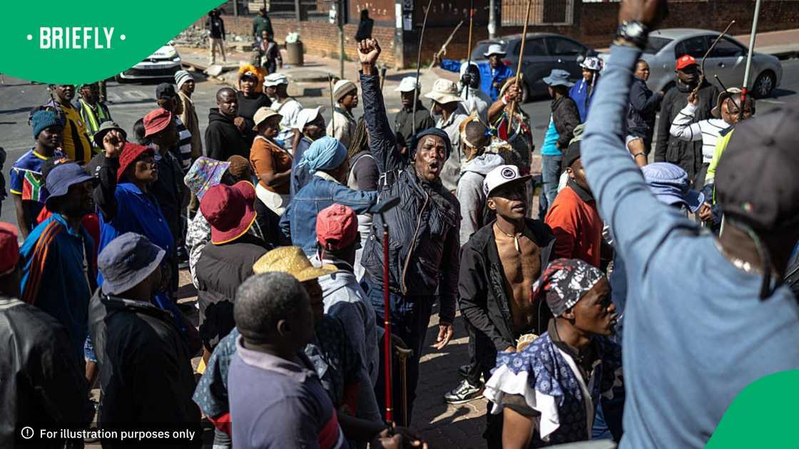 Protesters gesture as they sing in front of the Department of Home Affairs offices during a demonstration calling for the removal of undocumented immigrants in Alexandra township on July 30, 2026