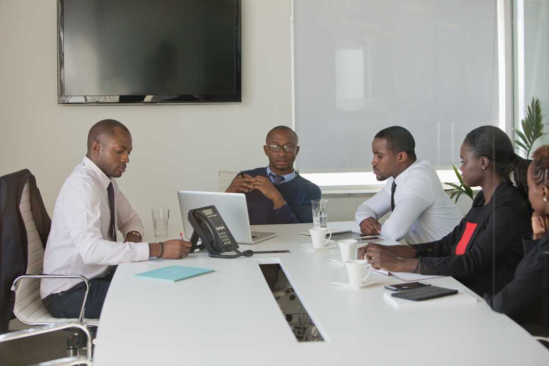 Managers listen to a call playback in a BPO office meeting.