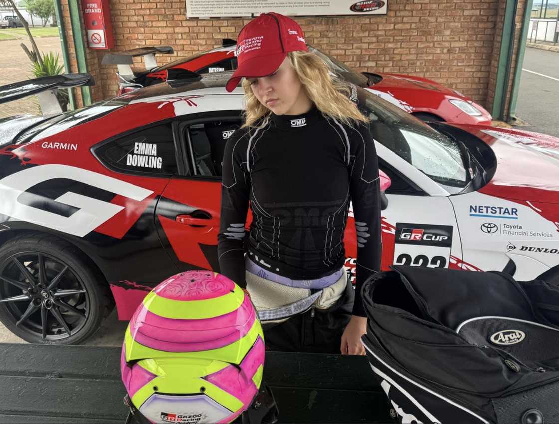 Emma-Rose Dowling stands beside her Toyota GR Cup race car in racing gear