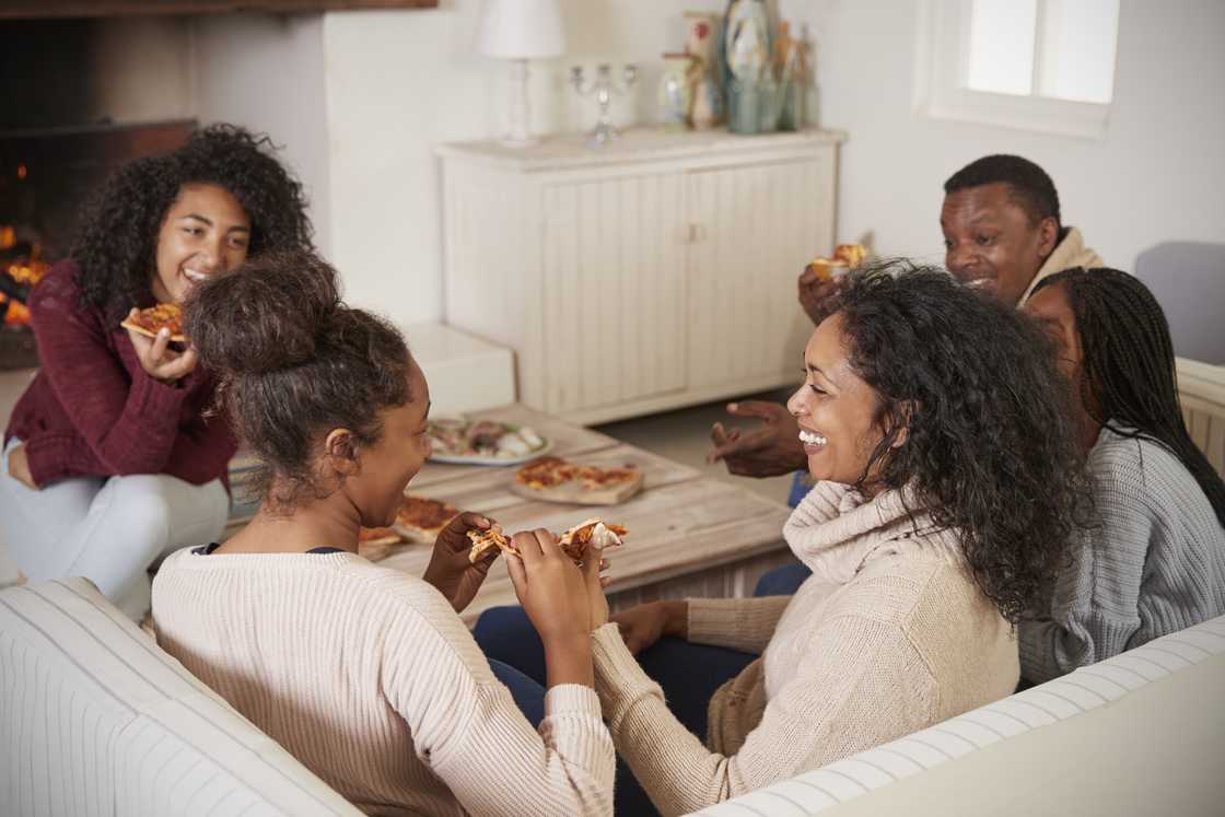 Family sitting on sofa eating pizza