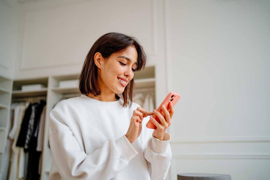 A woman smiling at her phone. A woman smiling at her phone.