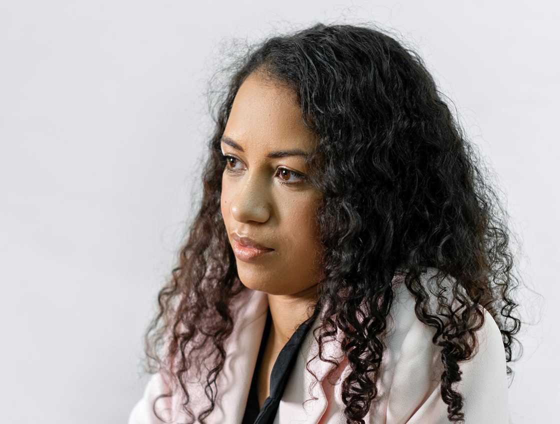 A woman looks thoughtfully to the side against a plain white background.