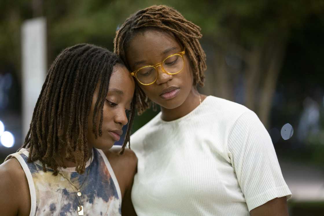 Two sad women are leaning on each other