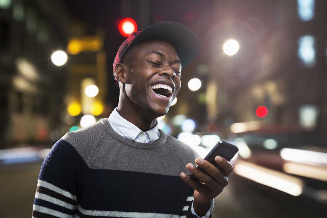 A man laughing at his phone. A man laughing at his phone.