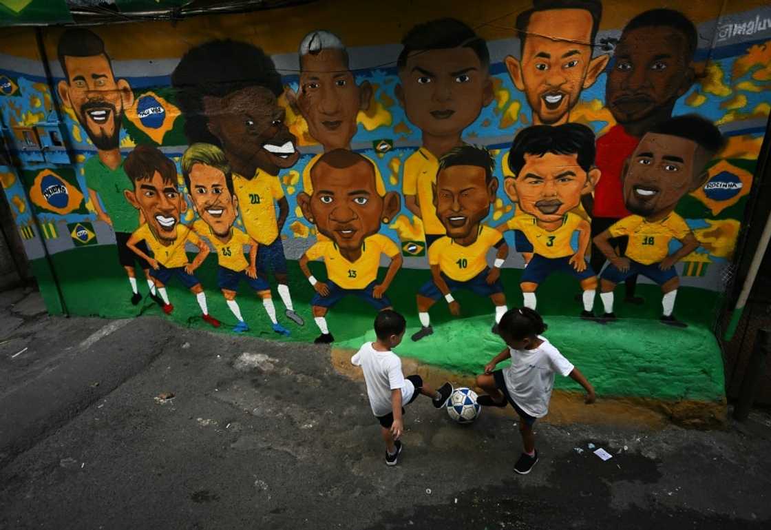 Children playing football in Rocinha in front of a mural of the national team