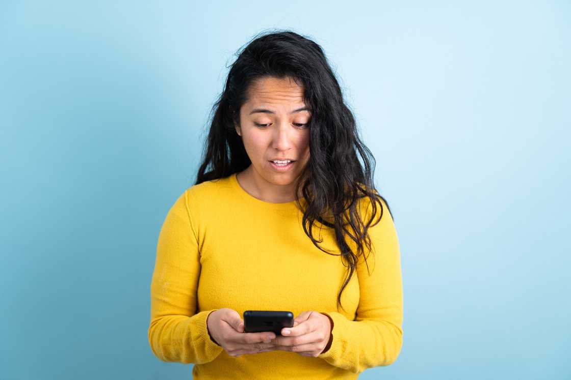 A confused woman looking at her phone.