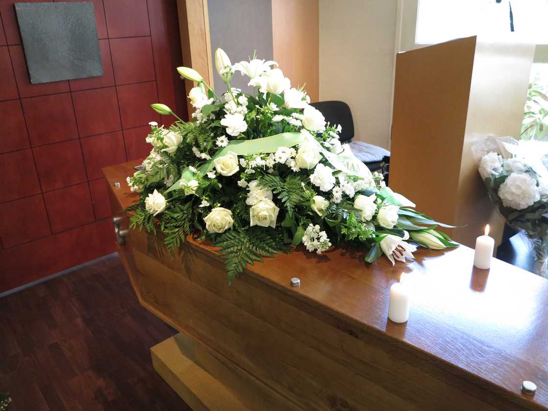 A closeup stock image of a funeral casket with flowers on top