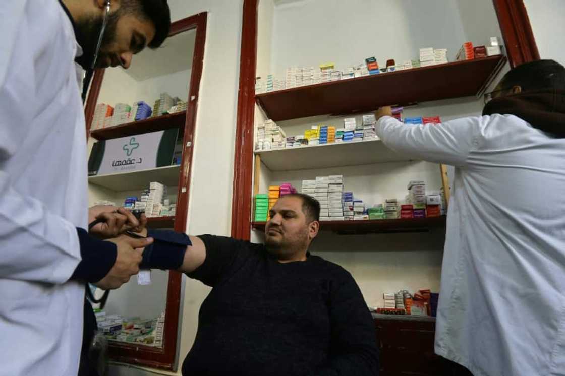 Mohammed Shasho (L) and Jaafar Mustafa test the blood pressure of a patient a medical centre in Damascus