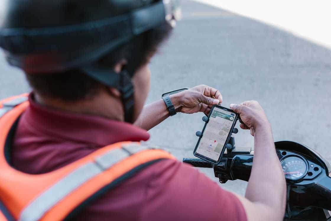 Motorbike delivery rider checking navigation on smartphone mount. Motorbike delivery rider checking navigation on smartphone mount.