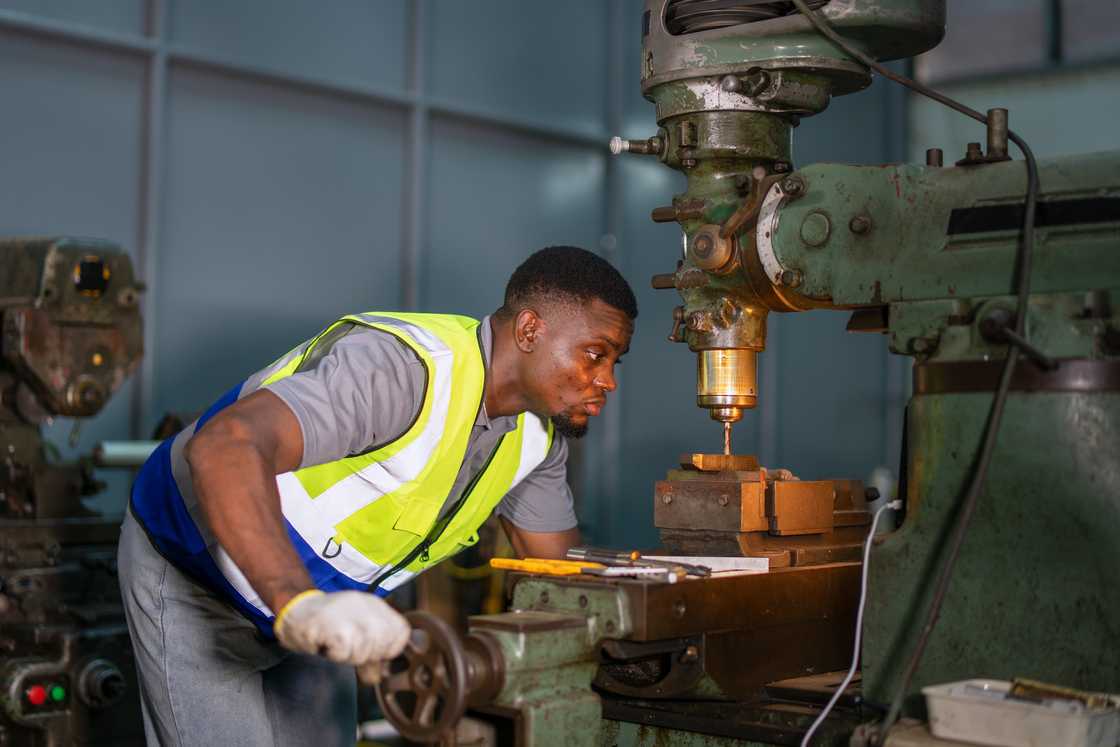 A male worker at a lathe machine shop. A male worker at a lathe machine shop.