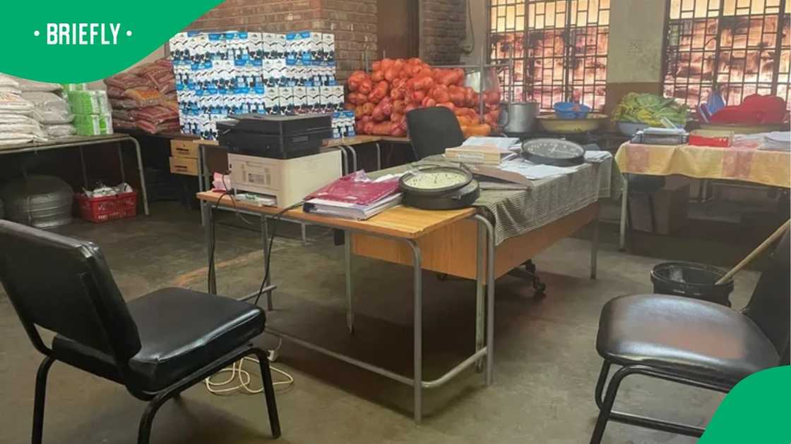 An untidy room at the school featured office chairs, printers, and clocks alongside sacks of produce stacked against a brick wall