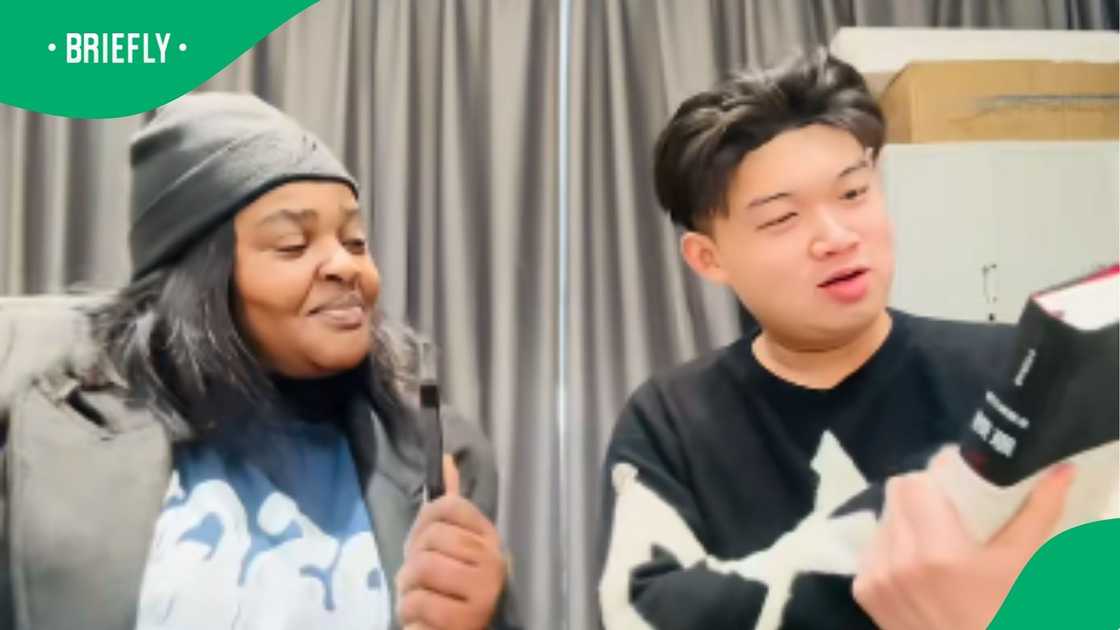 The picture captured a Chinese man holding a book, with a Venda woman right besides him The picture captured a Chinese man holding a book, with a Venda woman right besides him