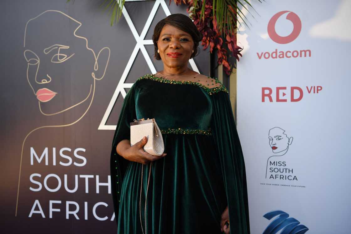 Thuli Madonsela at an event's red carpet wearing a long green dress and holding a white purse. Thuli Madonsela at an event's red carpet wearing a long green dress and holding a white purse.