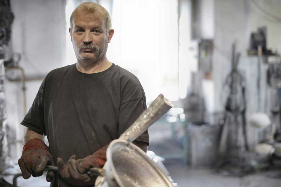 Male metallurgist working with metal in workshop Male metallurgist working with metal in workshop