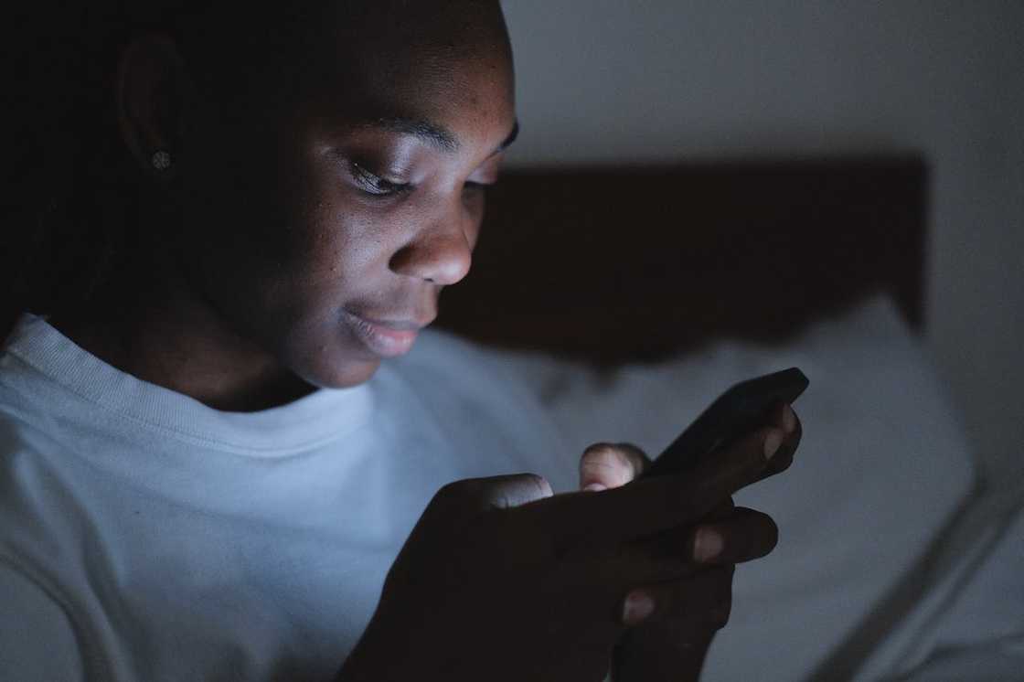 A woman looks at her phone screen in low light.