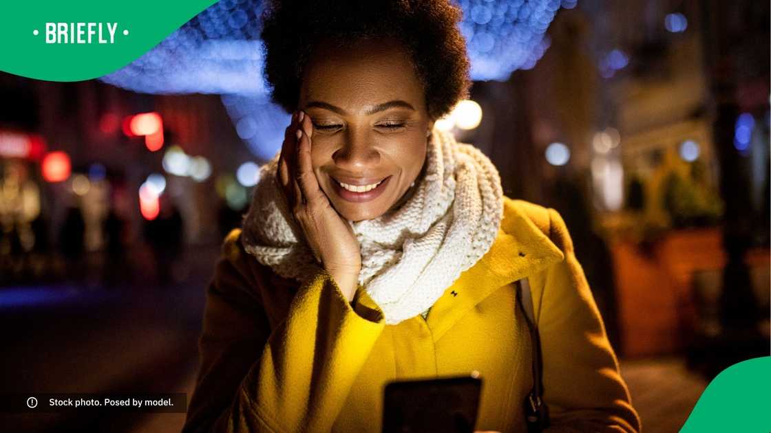 A woman smiling at her phone. A woman smiling at her phone.