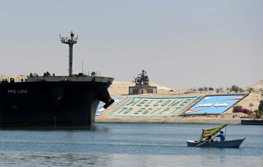 A file photo taken on May 27, 2021 shows a small boat sailing in front of a ship in Egypt's Suez Canal A file photo taken on May 27, 2021 shows a small boat sailing in front of a ship in Egypt's Suez Canal