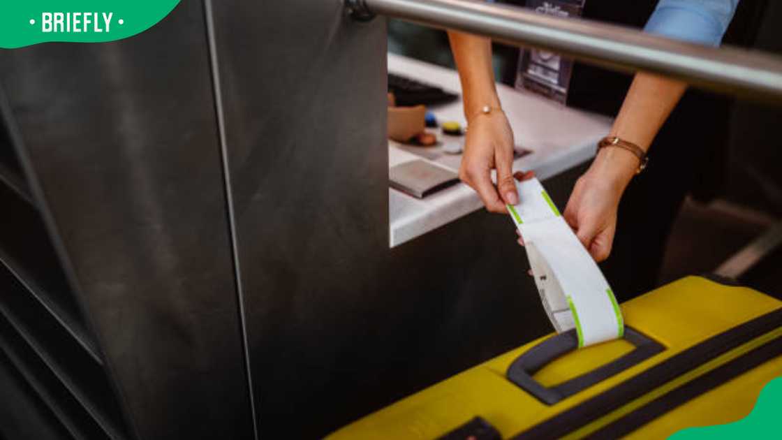 Airport check-in counter employee attaching tag on luggage