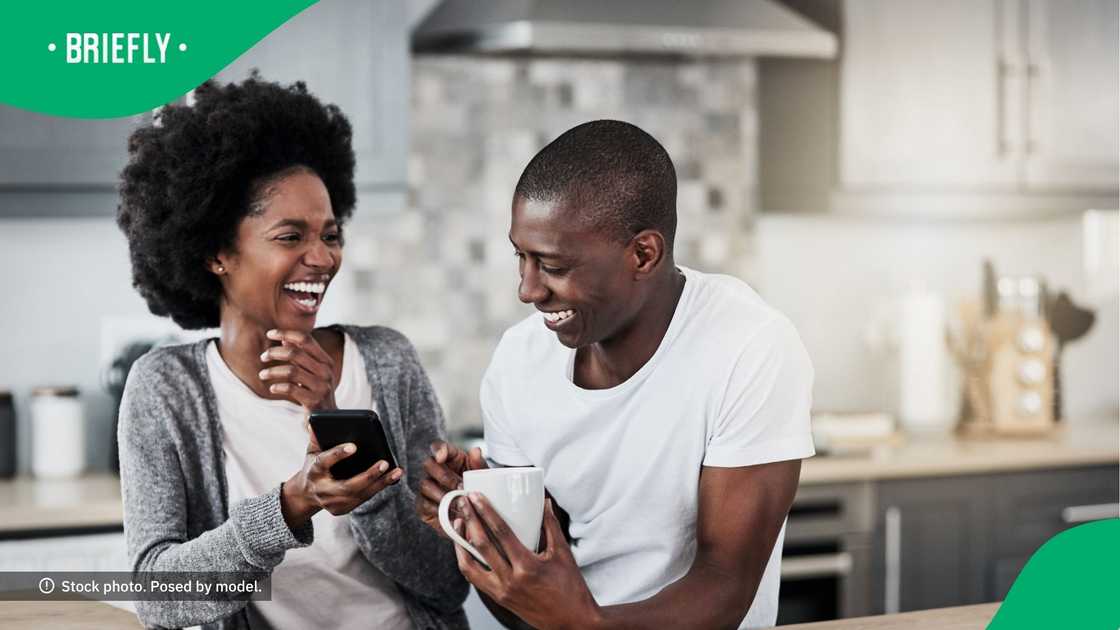 A couple laughing at content on a phone.