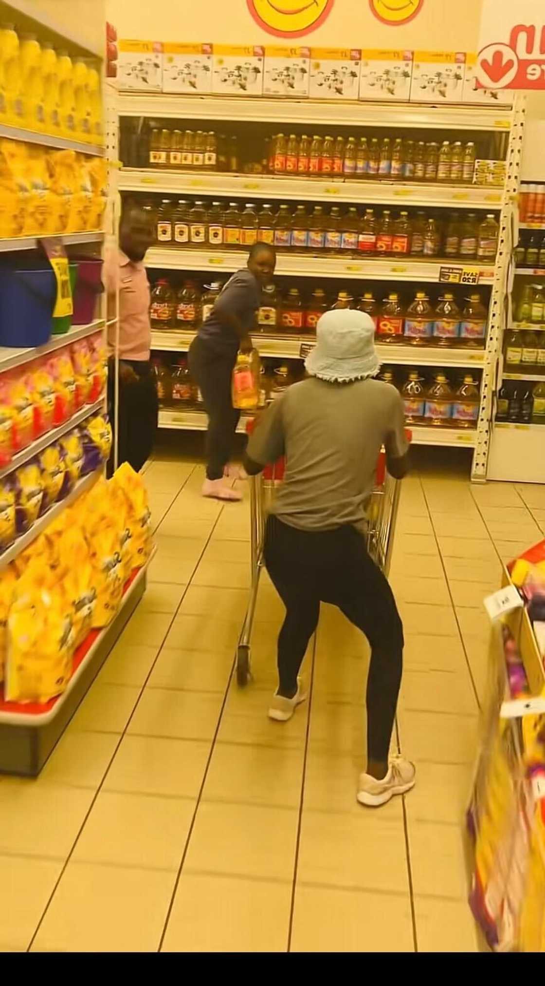 Two young women pushing and gebbing gocery items in a shop during a trolly dash.