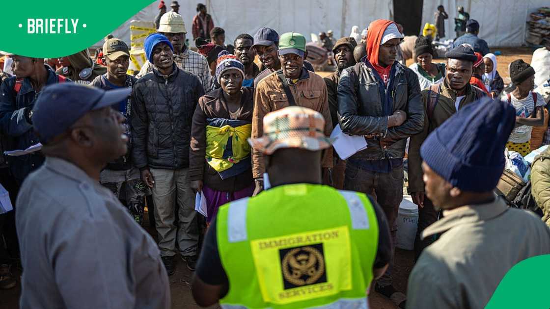 People awaiting repatriation stand to be called to board a bus headed to Zimbabwe at a repatriation centre in Musina near the Beitbridge border crossing with Zimbabwe on July 9, 2026