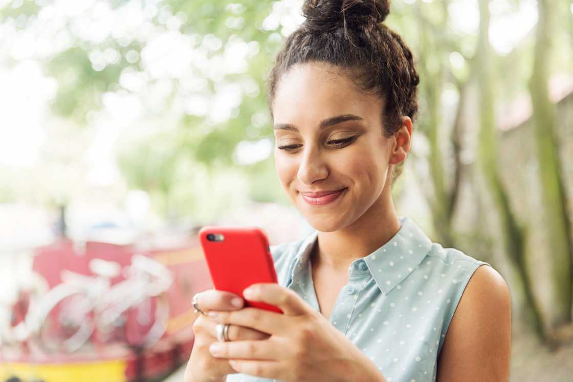 A woman smiling at her phone.