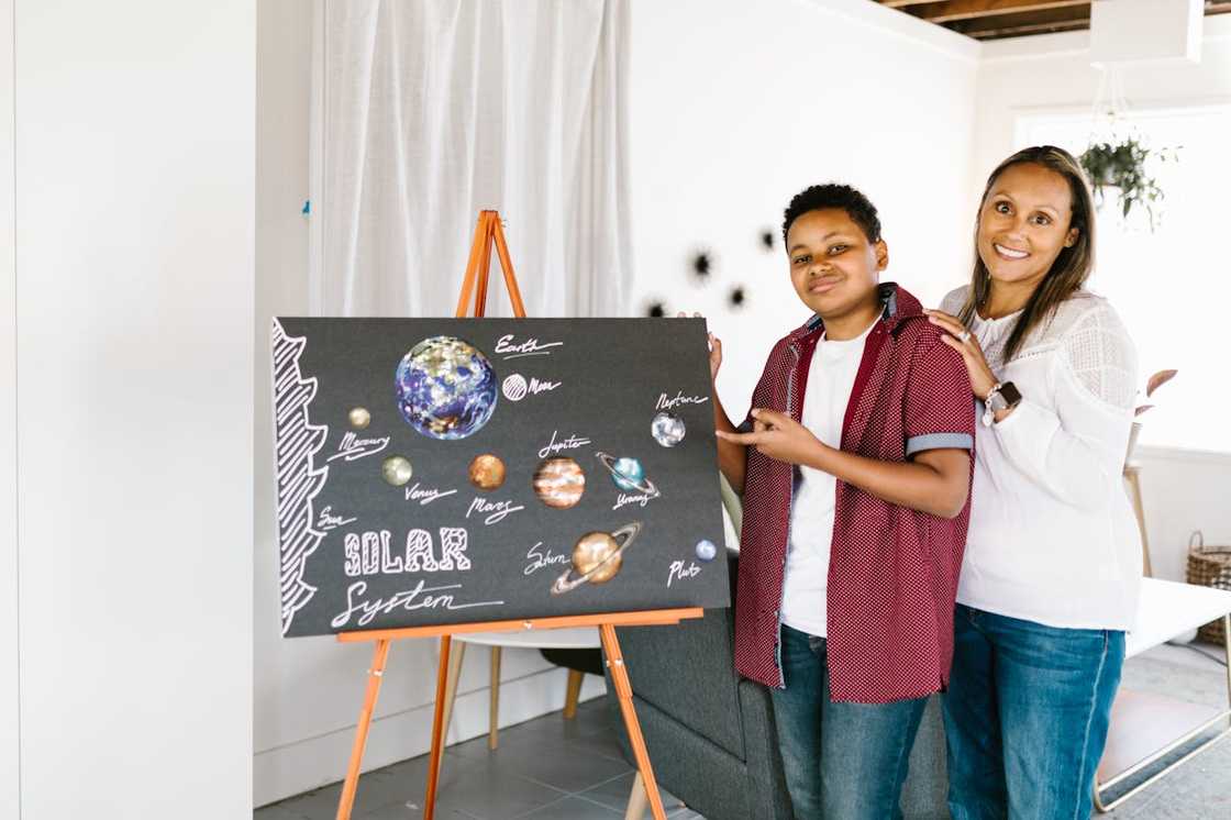 A child presents a painting project with an adult beside him.
