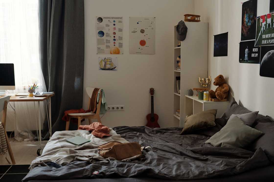 Unmade bed with study desk and science posters in a cosy bedroom. Unmade bed with study desk and science posters in a cosy bedroom.