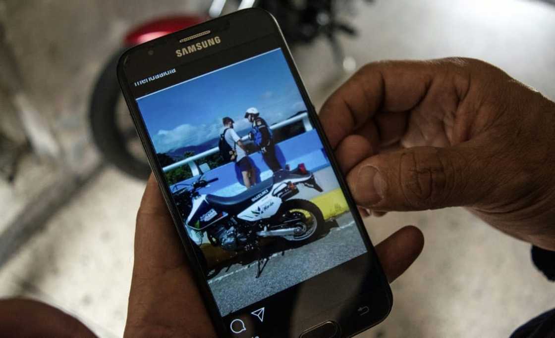 Venezuelan firefighter Henry La Cruz shows a picture of him speaking with a young man who was trying to commit suicide and whom he managed to rescue