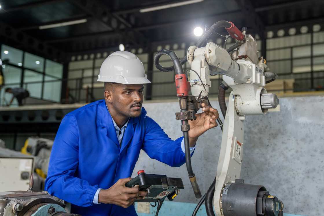 A young engineer working at a robotic arm. A young engineer working at a robotic arm.