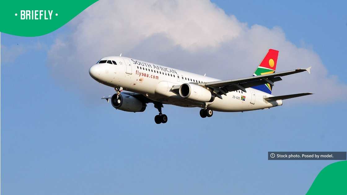 A South African Airways passenger plane flew through a partly cloudy blue sky with its landing gear deployed.