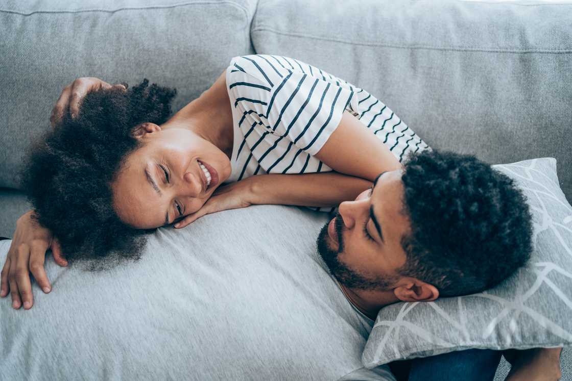 A young couple lying together on their sofa at home. A young couple lying together on their sofa at home.