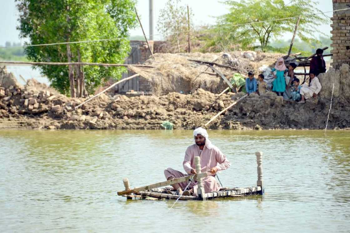 A man uses a makeshift raft to cross s stream of flood waters near his damaged house in Jaffarabad, Pakistan A man uses a makeshift raft to cross s stream of flood waters near his damaged house in Jaffarabad, Pakistan