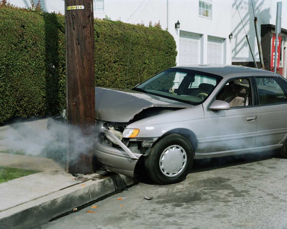 A car crashed into a pole on a road.